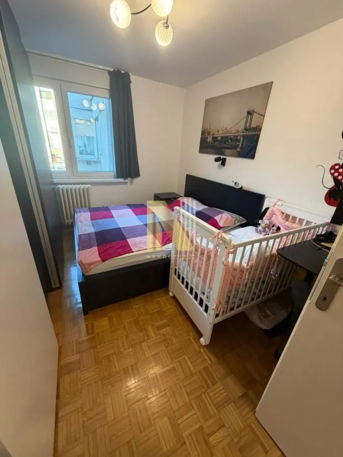 Spavaća soba sa bračnim krevetom i krevecom za bebe.