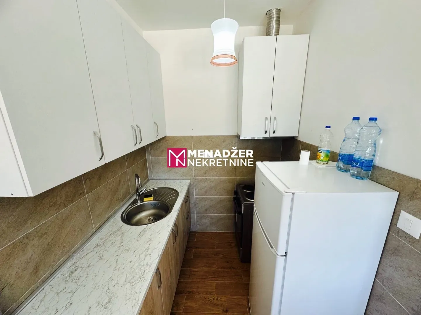 Smaller equipped kitchen with white cabinets and a refrigerator.