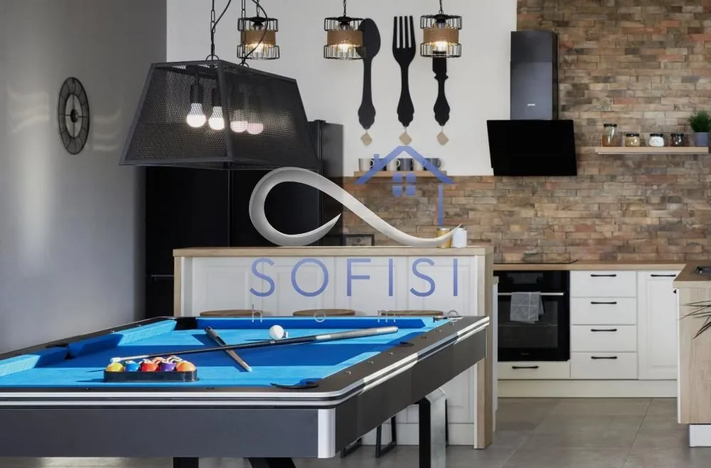 Living room with a pool table and a kitchen in the background.