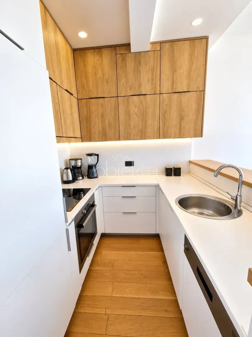 Small modern kitchen with wooden cabinets and white countertops.