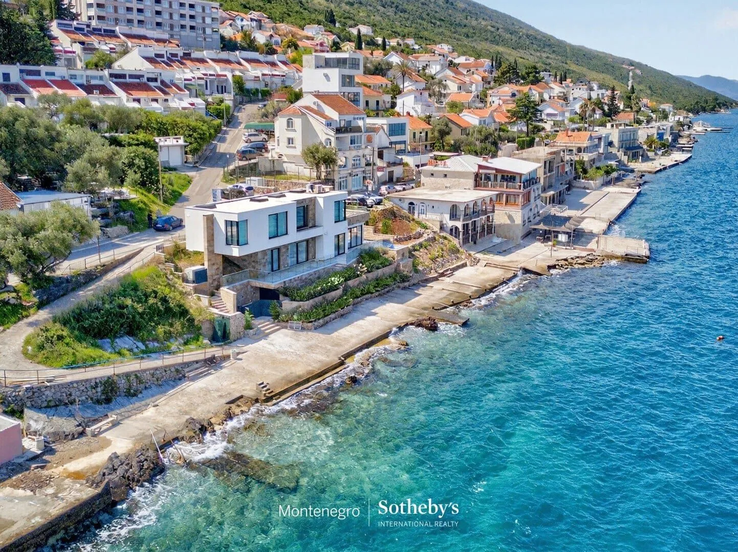 Pogled iz vazduha na obalu sa kućama i plavim morem.