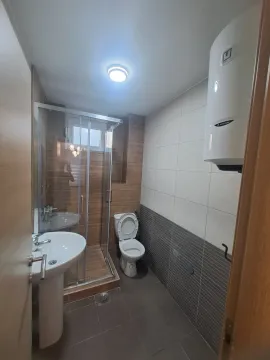 Bathroom equipped with a washbasin, toilet, shower cabin, and water heater. - image 4