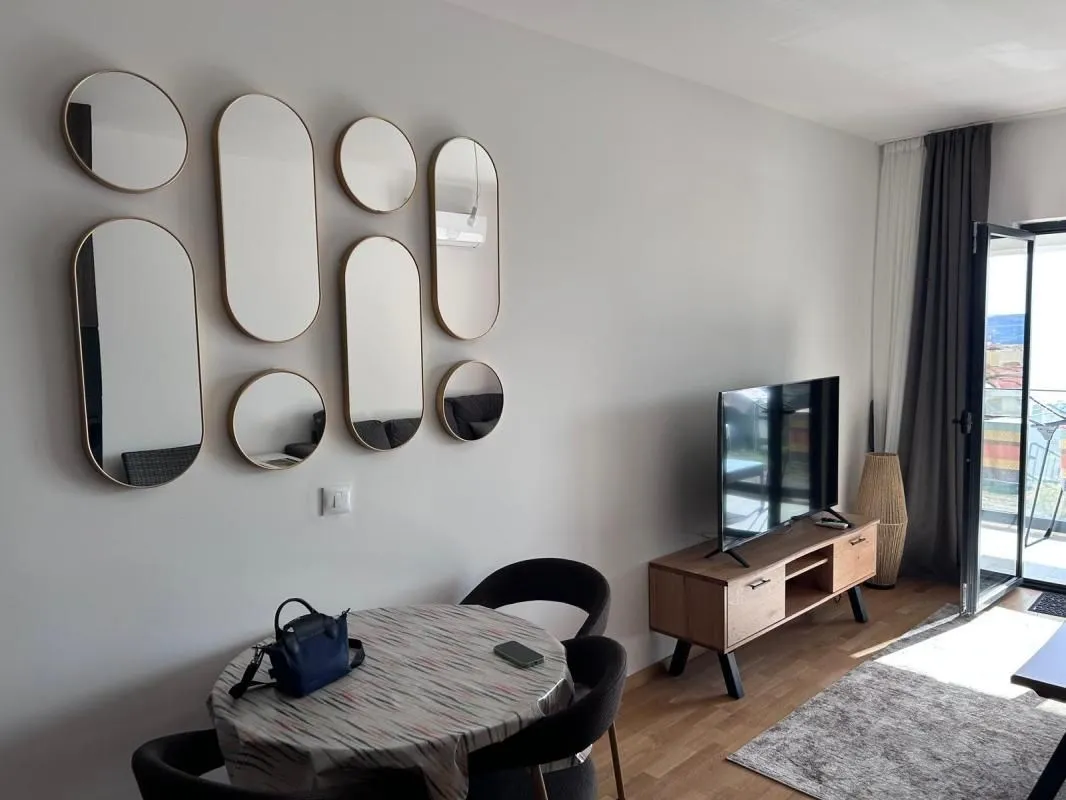 Living room with a dining table and decorative wall mirrors.