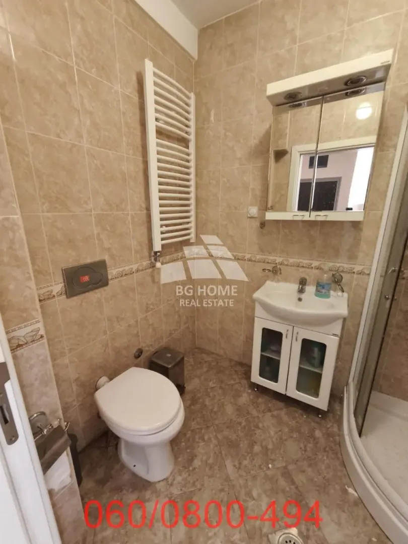 Compact tiled bathroom featuring a shower cabin, vanity with sink, and a toilet.