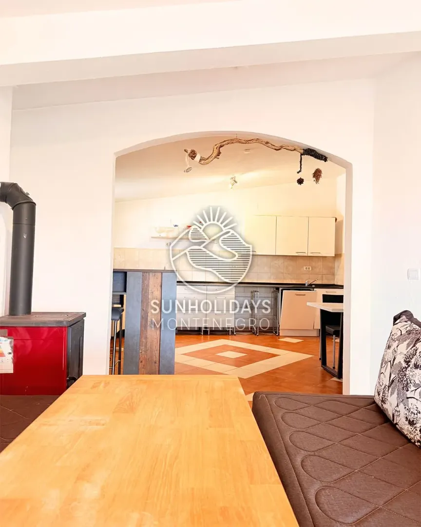 Living room with a wooden table and a view of the kitchen.