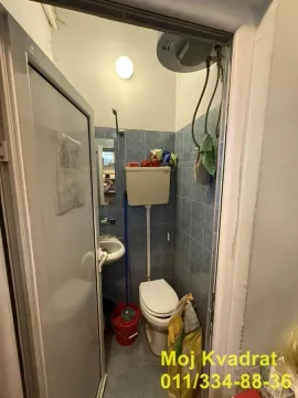 Small bathroom with tiles, toilet, and a small washbasin. - image 5