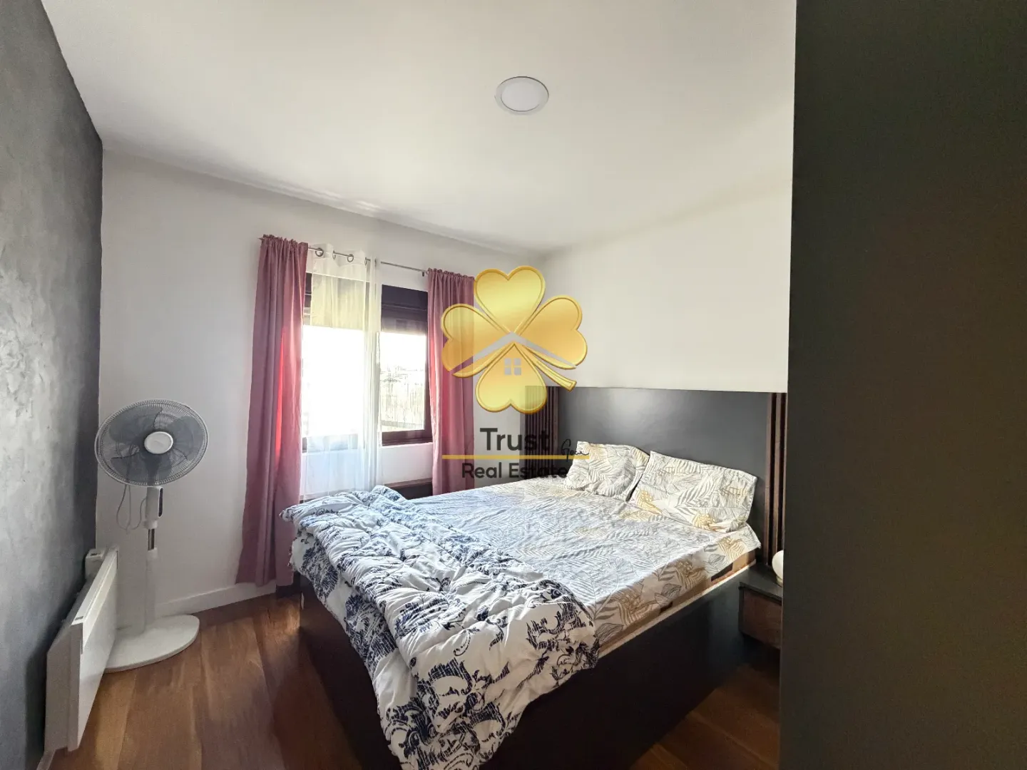 Furnished bedroom with a double bed, window, and fan.