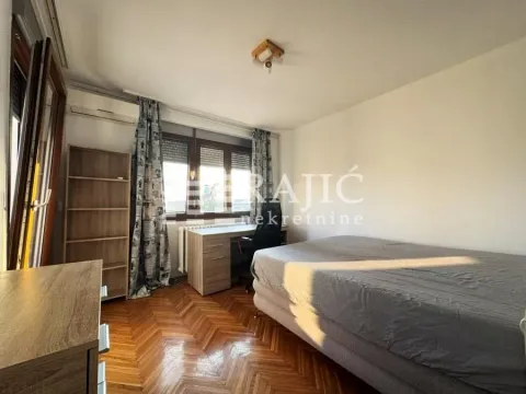 Furnished bedroom with a bed, desk, and shelves. - image 4