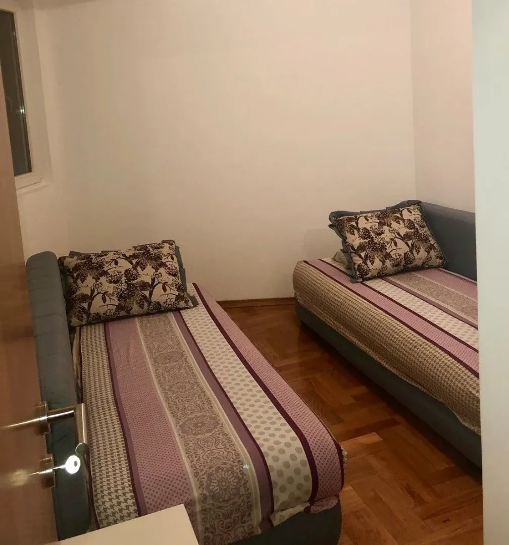 Spavaća soba sa dva singl kreveta i drvenim podom.