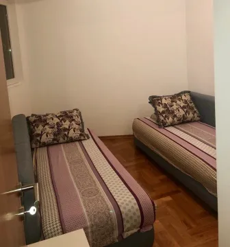 Spavaća soba sa dva singl kreveta i drvenim podom. - image 7