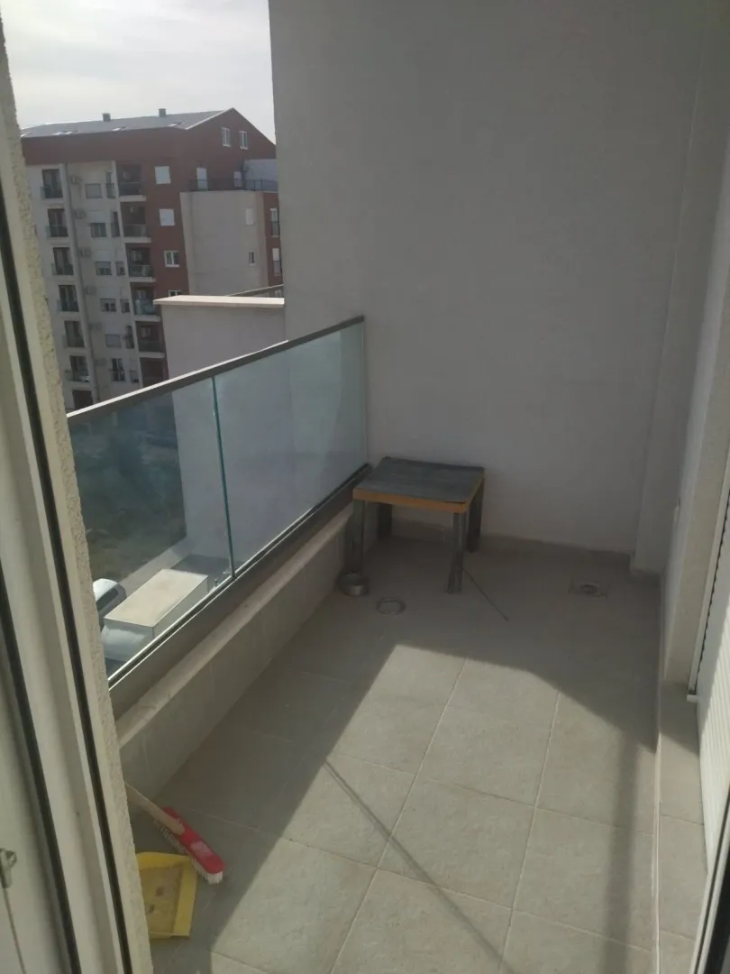 Small empty balcony with a glass railing and a view of the building.