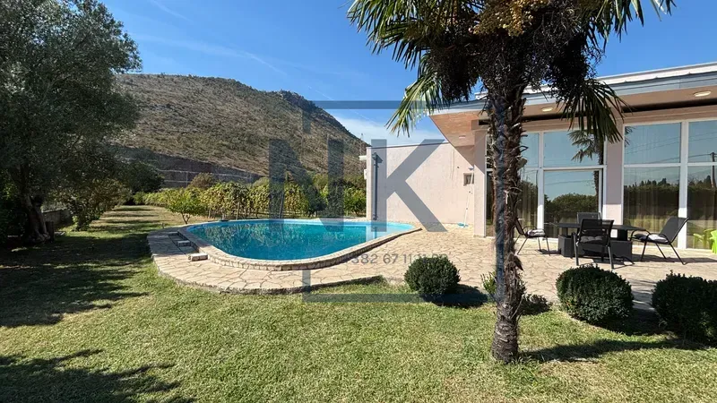 Exterior of the house with a swimming pool, landscaped yard, and nature view.