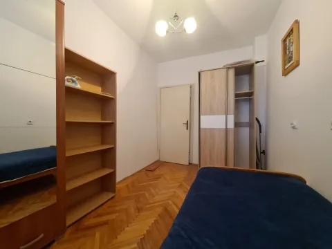 A simply furnished bedroom with wooden parquet flooring and wardrobes. - image 8