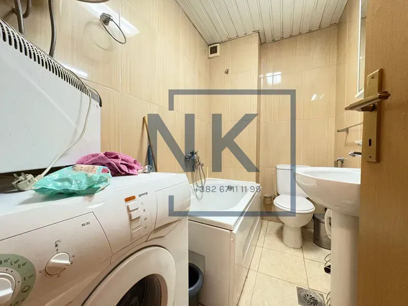 Smaller bathroom with a bathtub, washbasin, toilet, and washing machine.
