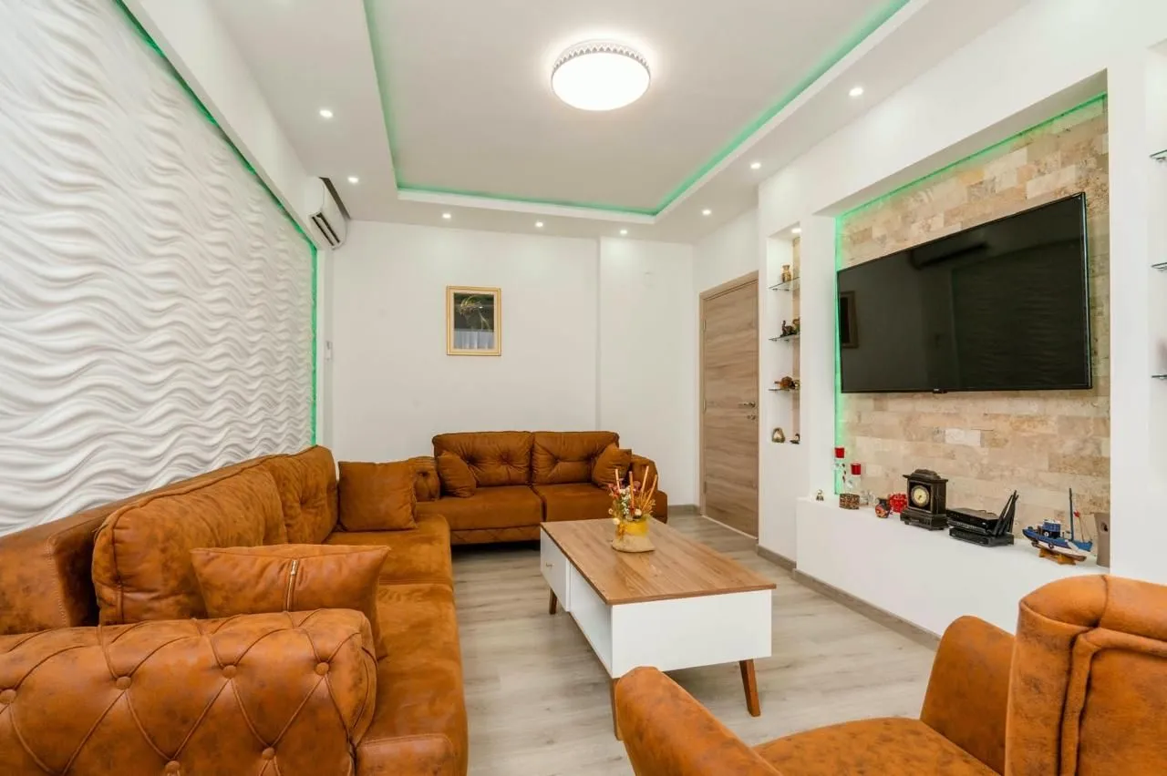 Modern living room with brown sofa set and wall-mounted TV.