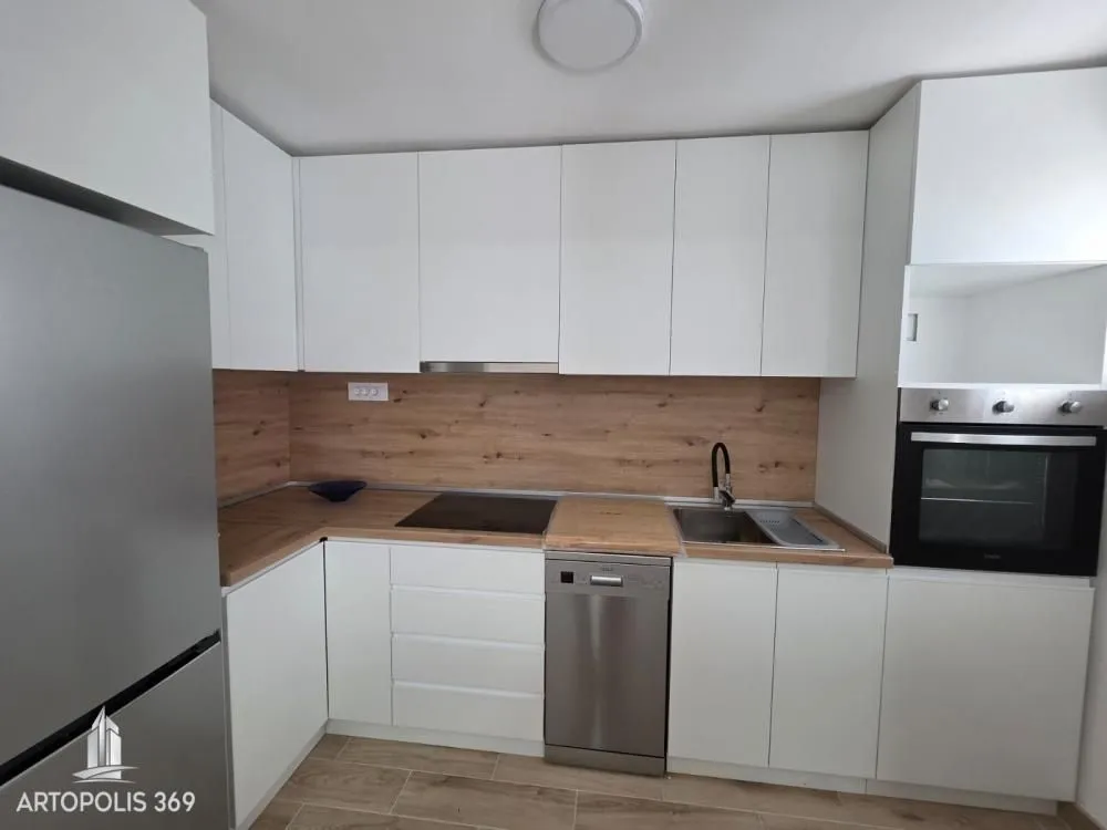 Modern white kitchen with a wooden countertop and built-in appliances.