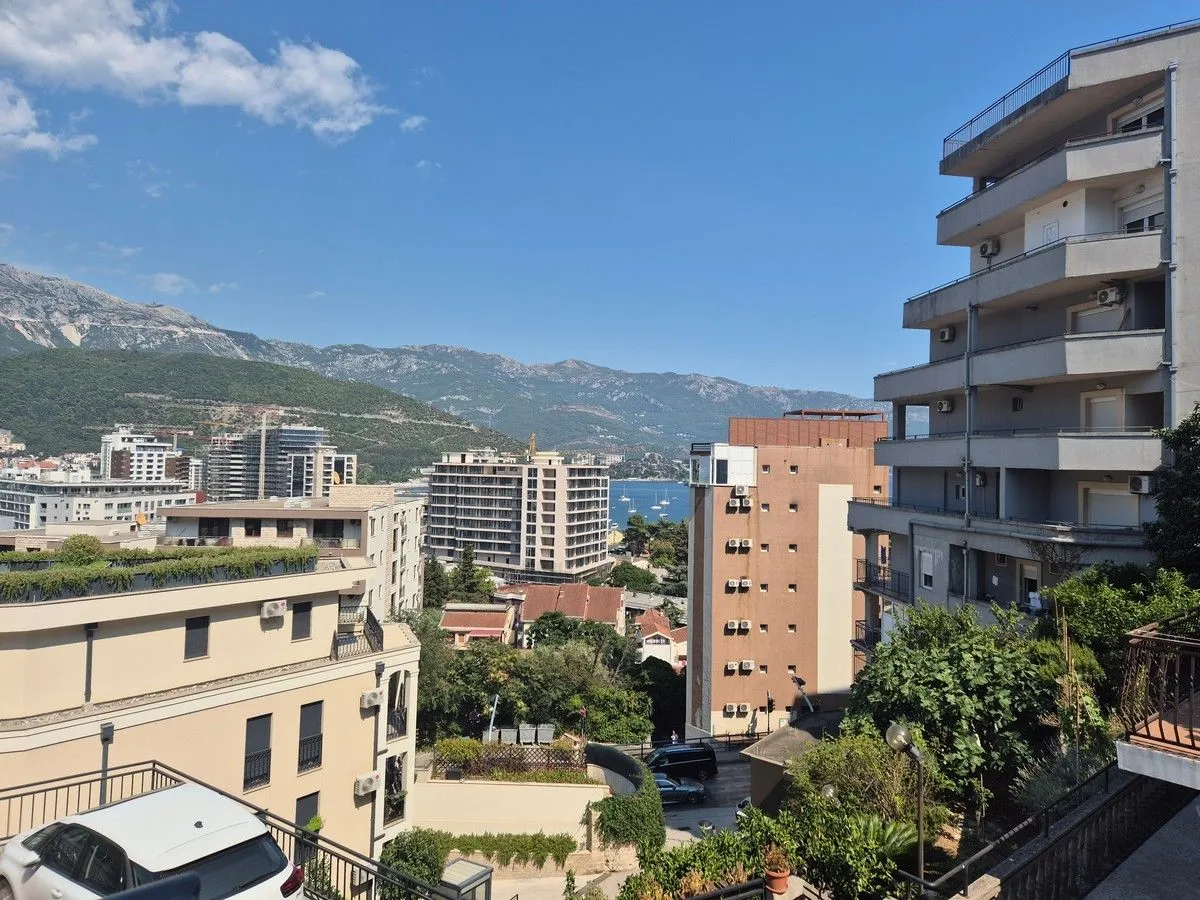 View from the terrace overlooking city buildings, surrounding mountains, and the sea.