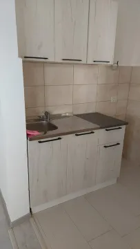 Smaller kitchen with light wood cabinets and ceramic tiles. - image 8