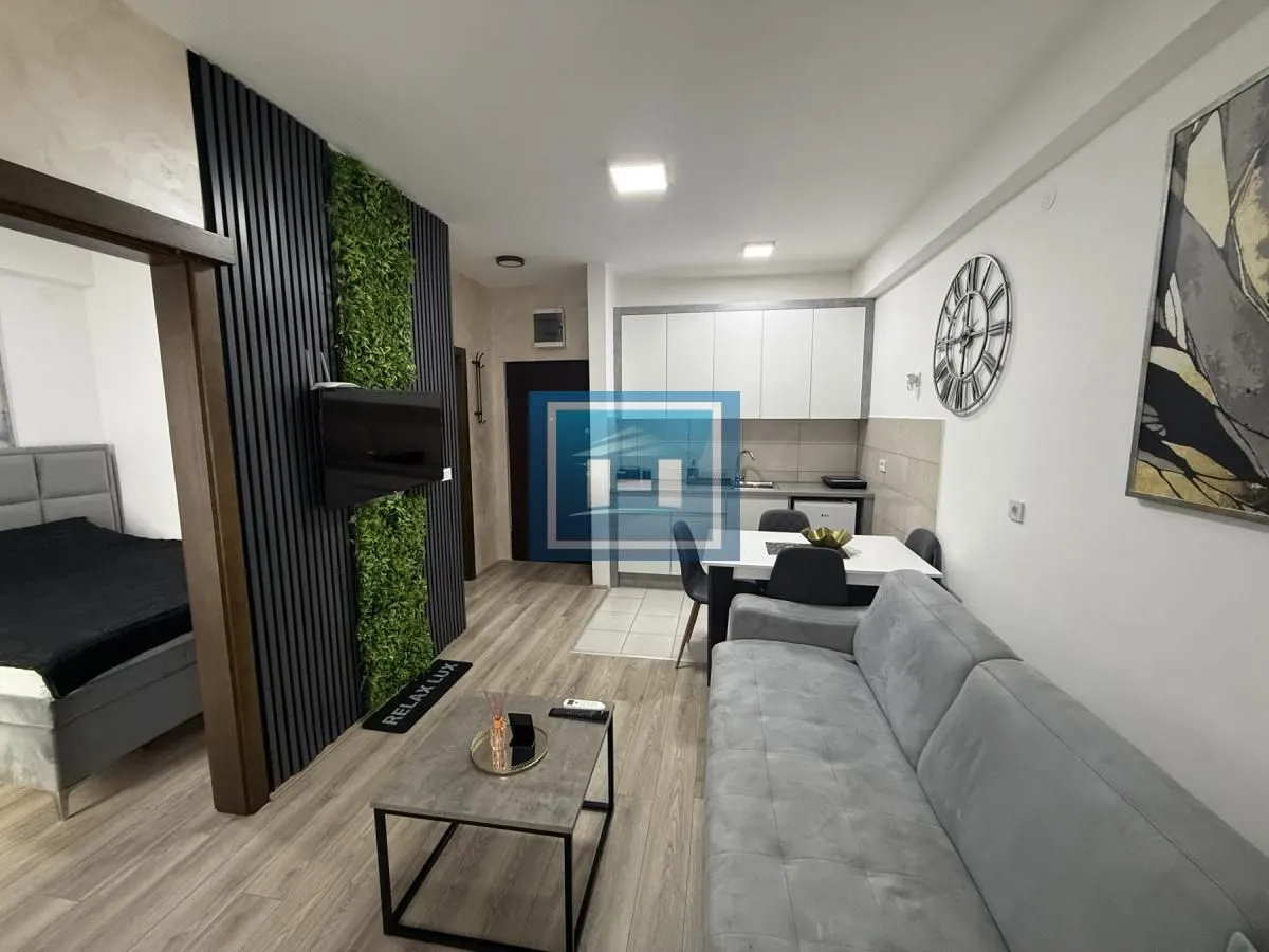Living room with a sofa, dining area, and kitchen in the background.