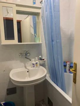 Small bathroom with a sink, mirror, and bathtub with a blue curtain. - image 6