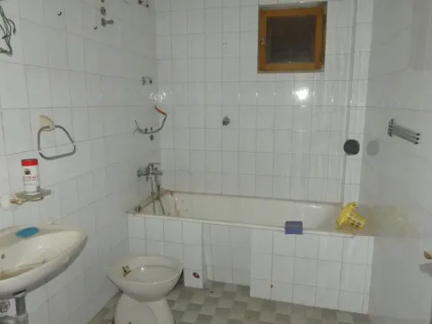 Older bathroom lined with white tiles featuring a bathtub, sink, and toilet bowl. - image 10