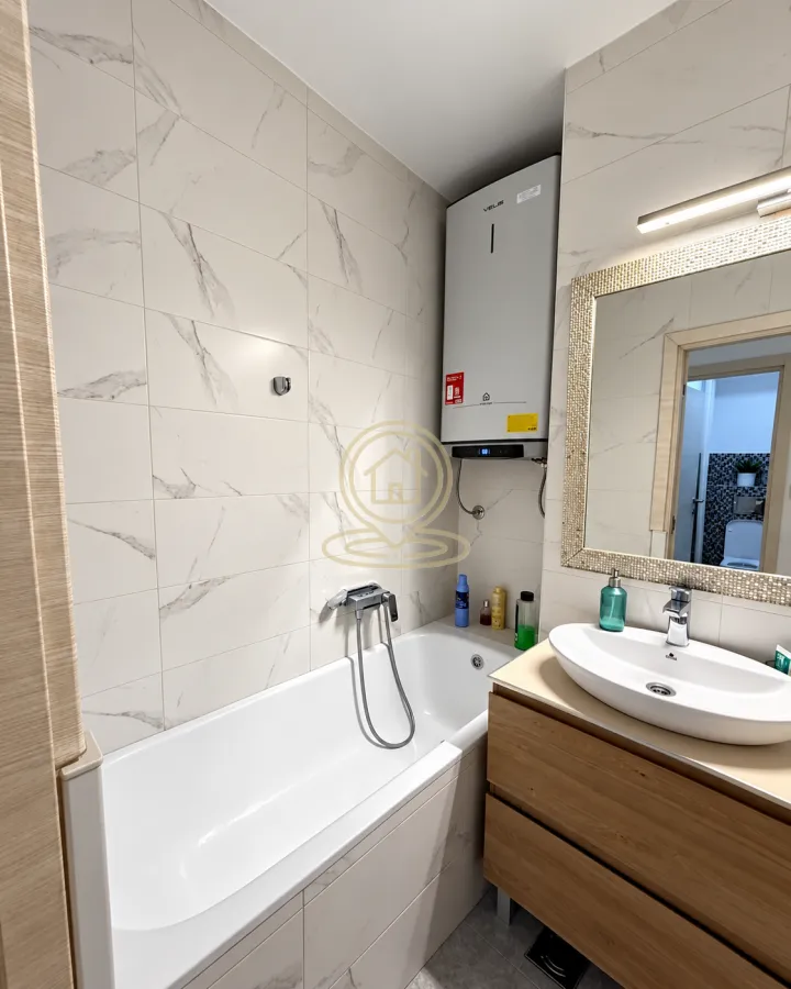 Bathroom equipped with a bathtub, vanity unit with washbasin, and water heater.