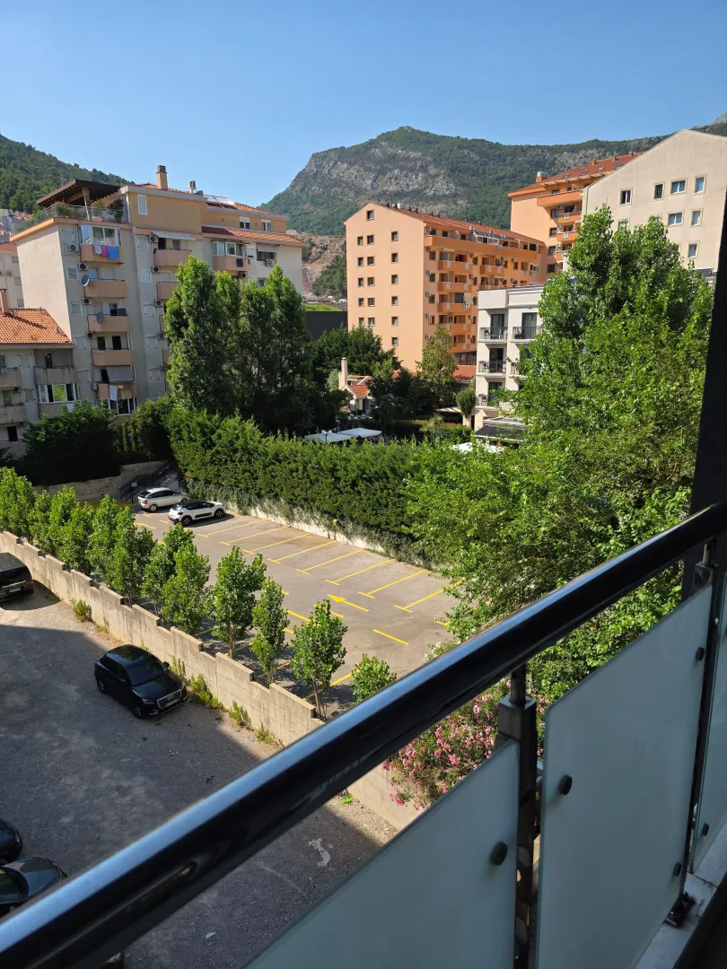 Pogled sa terase na zgrade, parking i okolne planine.