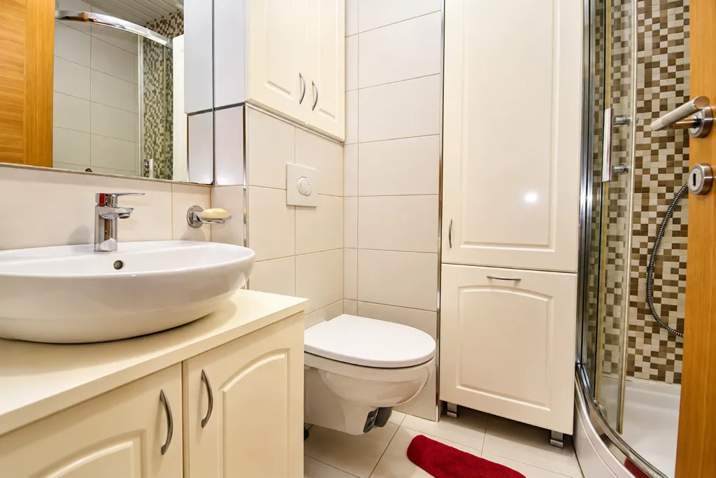 Bright bathroom with a washbasin, toilet, and shower cabin.