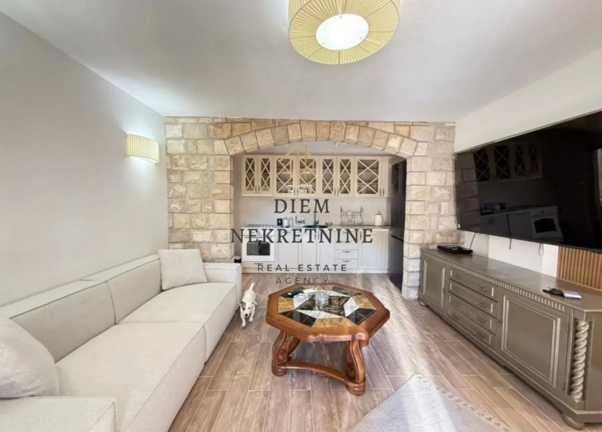 Living room with a sofa and dining area in the background.