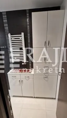 Pogled na kupatilo sa belim elementima i ormarićima.