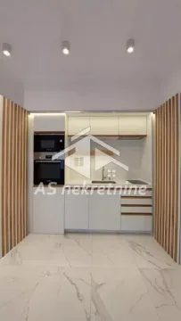 Moderna bela kuhinja sa ugrađenim uređajima i drvenim dekorativnim detaljima. - image 2