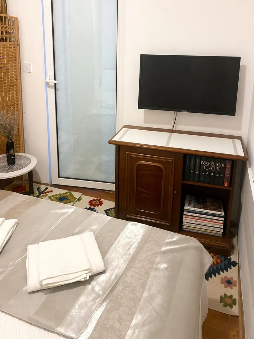 Spavaća soba sa krevetom, komodom i zidnim televizorom.