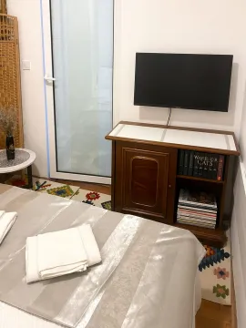 Spavaća soba sa krevetom, komodom i zidnim televizorom. - image 4