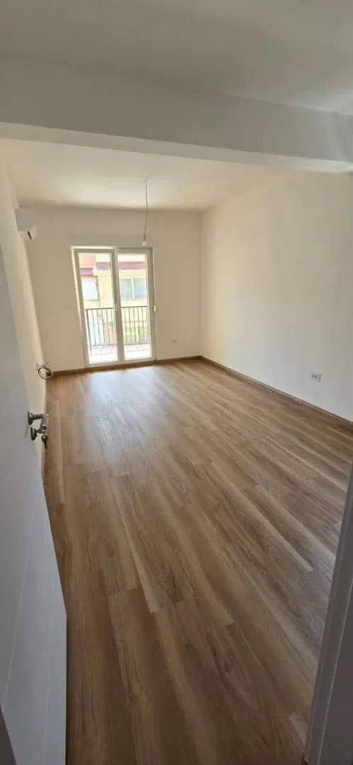 Prazna soba sa laminatom i izlazom na terasu.