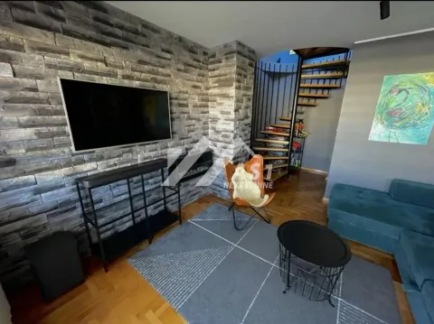 Dnevna soba sa klesanim kamenim zidom, televizorom i kružnim stepeništem. - image 3