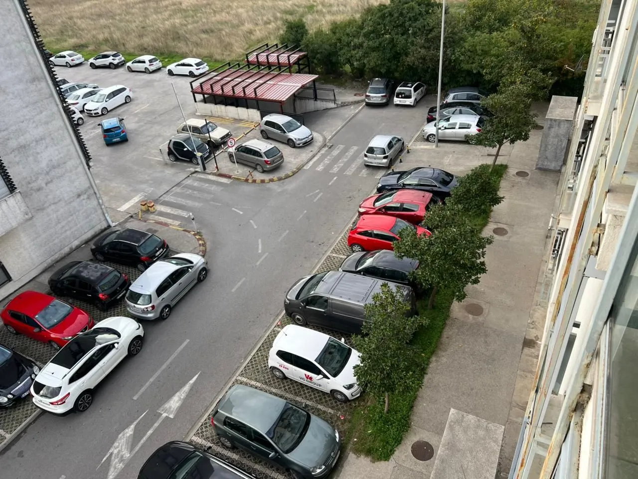 Pogled odozgo na parking ispred zgrade sa parkiranim automobilima.