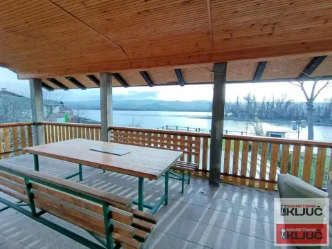 Covered terrace with a wooden table and benches and a river view. - image 7