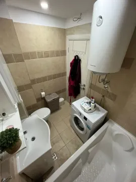 Bathroom equipped with a bathtub, washbasin, toilet, and washing machine. - image 10
