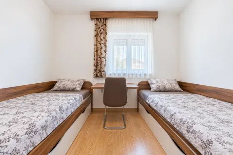 Bedroom with two single beds and a desk. - image 4