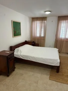 A bedroom with a double bed, wooden nightstands, and windows with curtains. - image 8