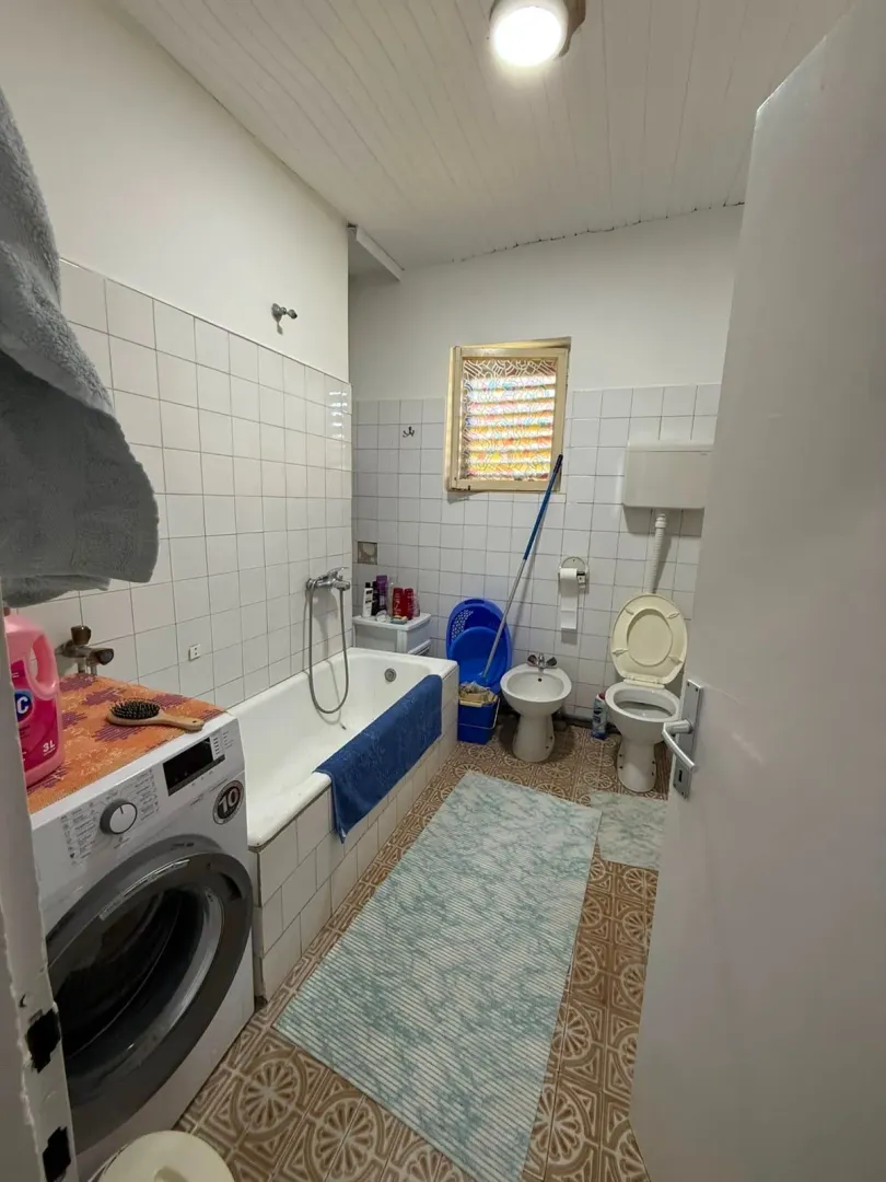 Bathroom with bathtub, washing machine, bidet, and toilet.