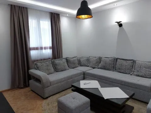 Living room with a corner sofa, coffee table, and a window with curtains. - image 8