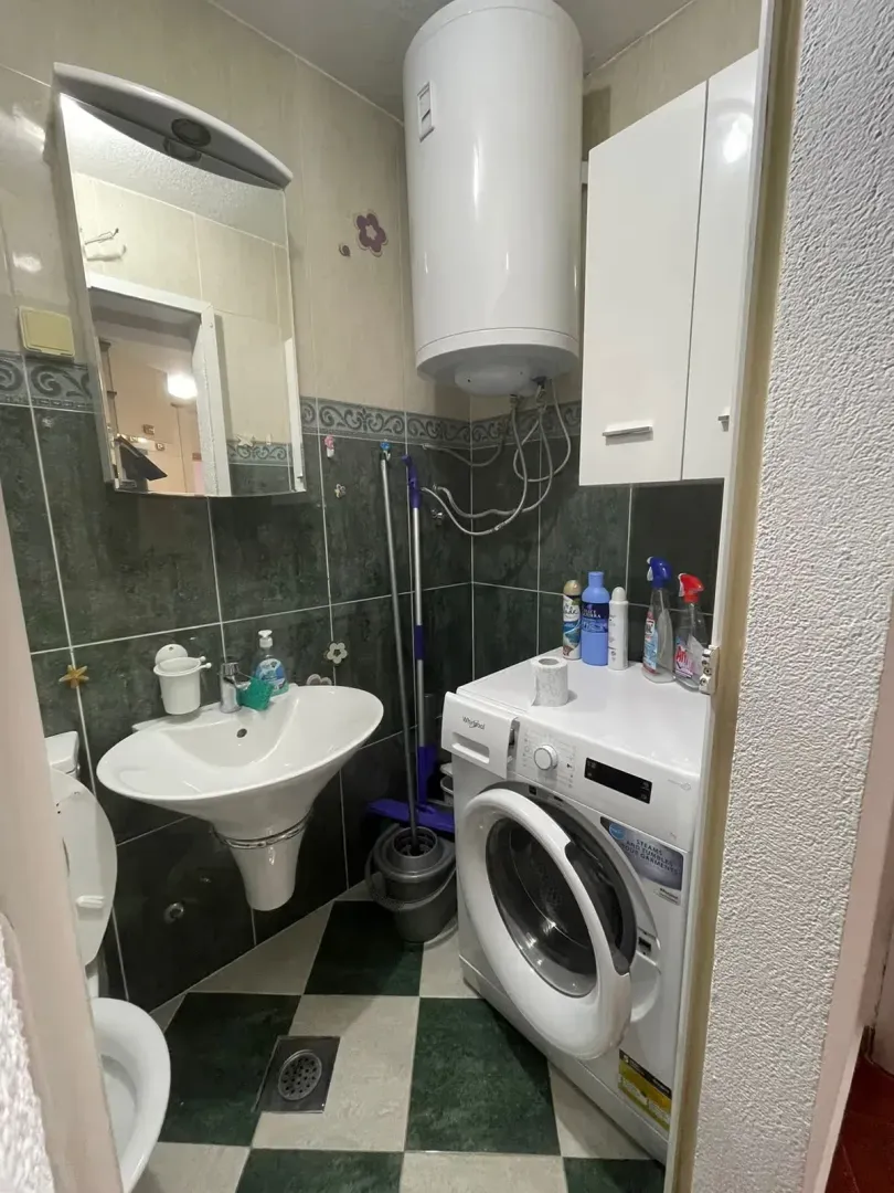 Manje kupatilo sa umivaonikom, WC šoljom, veš mašinom i bojlerom.