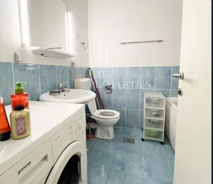 Bathroom with blue tiles, a washing machine, and white sanitaryware. - image 5