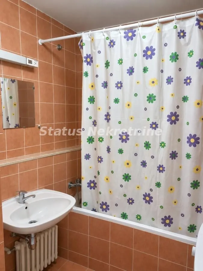 Kupatilo sa kadom, umivaonikom i narandžastim zidnim pločicama.