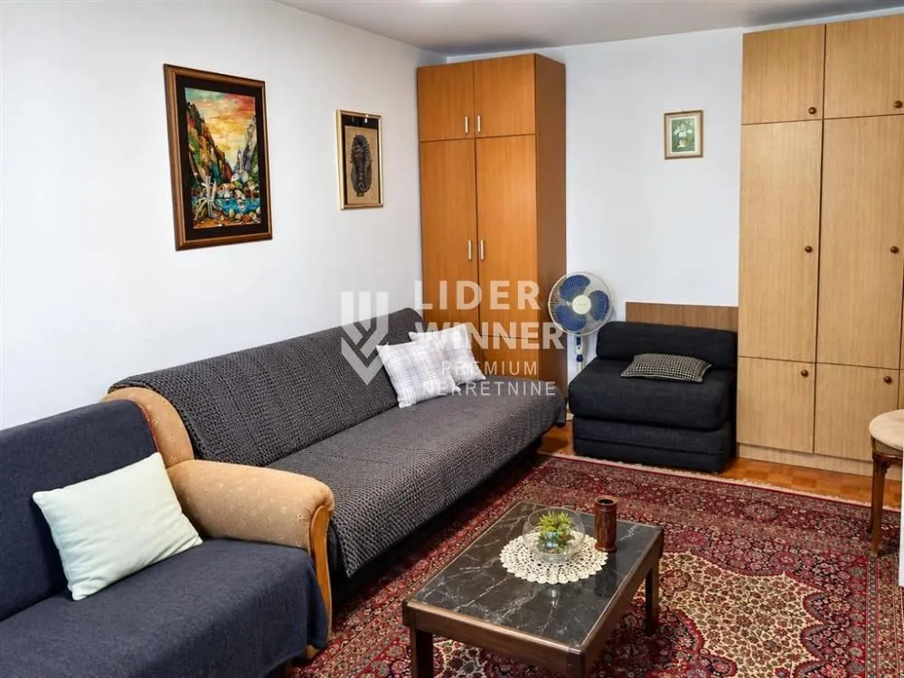 Dnevna soba sa garniturom za sedenje, klub stočićem i ormarima.