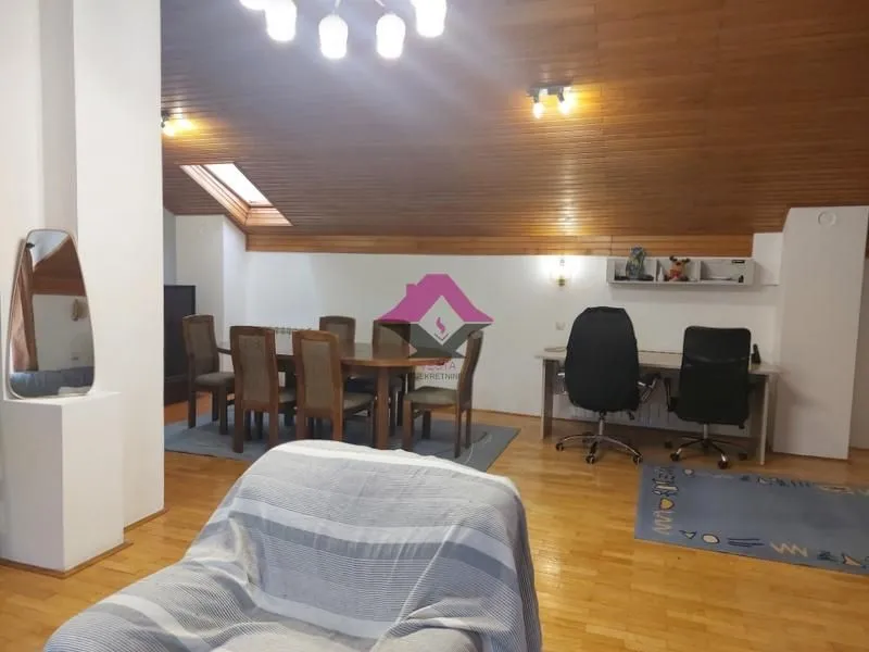 Prostrana dnevna soba sa drvenim krovom, trpezarijskim stolom i radnim kutkom.