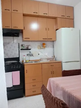 Manja kuhinja sa drvenim elementima, šporetom i frižiderom. - image 4