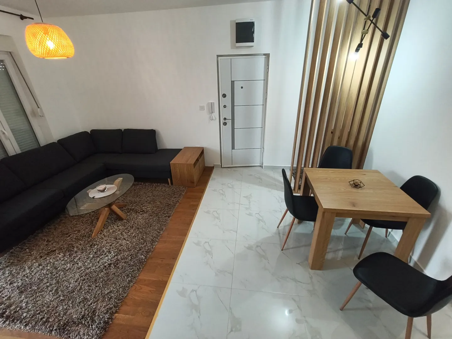 Living room with sofa, dining table, and entrance door.
