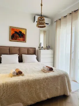 Svijetla spavaća soba sa bračnim krevetom, bijelom komodom i dekorativnim detaljima. - image 3